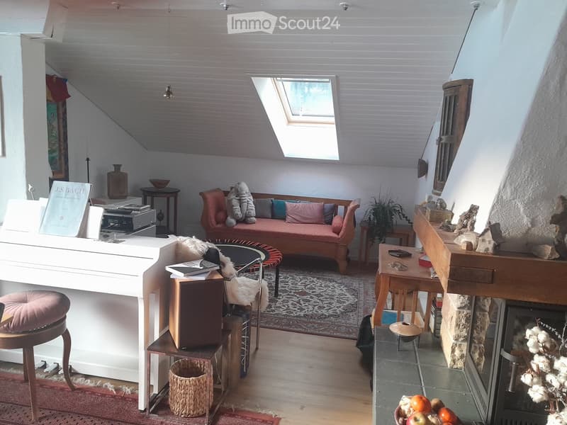 A cozy, well-furnished room with a fireplace, a sofa, a piano, and various decorative items including vases and artwork.