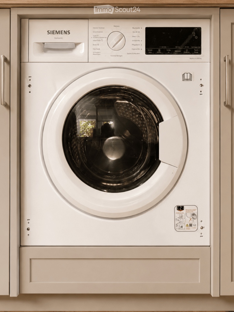 A white Siemens washing machine with a control panel and a transparent drum, integrated into a cabinetry setup.