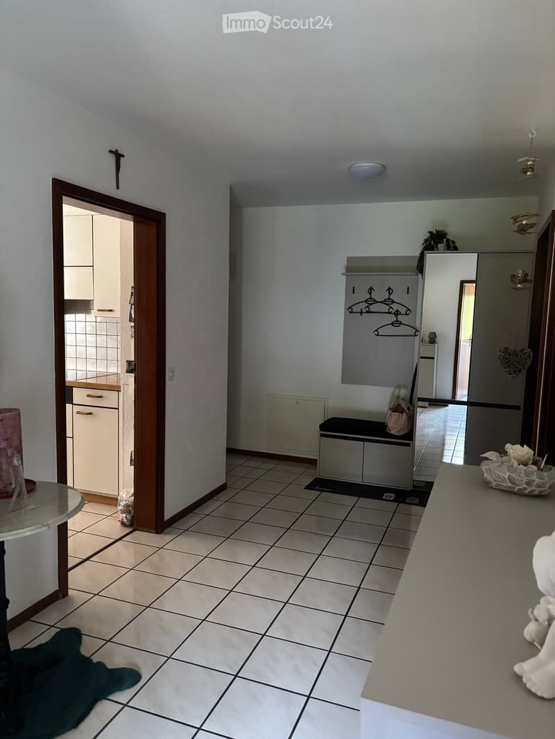 Hallway with tiled floor, coat rack, small table, and open doors leading to other rooms.