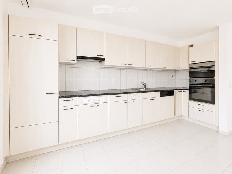 Modern kitchen with white cabinets, tiled backsplash, and stainless steel appliances including an oven and dishwasher.