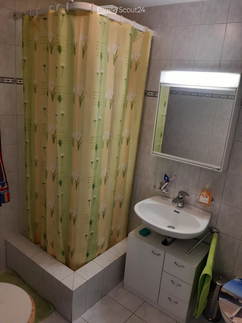 Bathroom with a white sink, mirror, cabinet, and a shower curtain with floral design.
