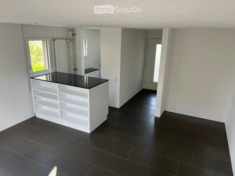 Empty room with white walls, dark tiled floor, white shelving unit, and a large window with blinds.