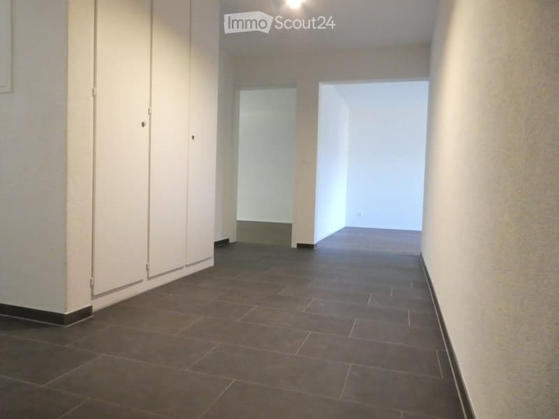 Empty hallway with tiled floor, white walls, and two doors leading to other rooms.