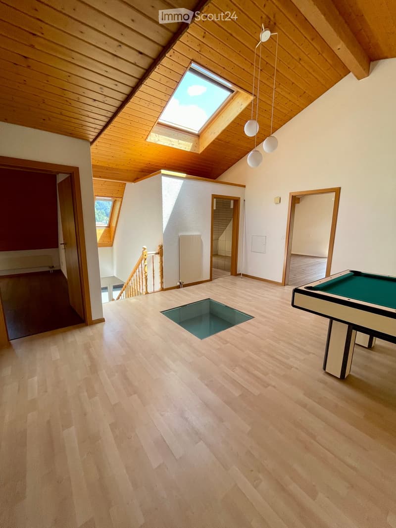 Spacious room with wooden floors, skylight windows, staircase, and a pool table.