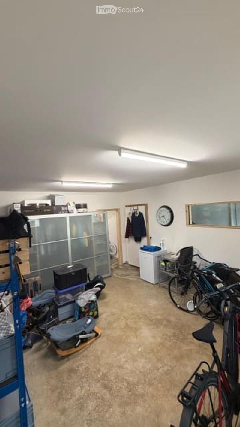 Garage with a cabinet, clock, bicycles, washing machine, and a small table.