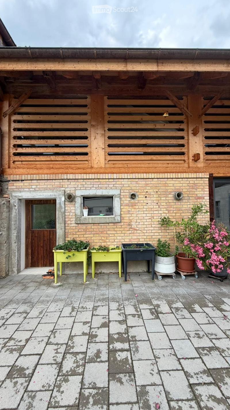 Outdoor patio with brick walls, wooden shutters, and potted plants on tables.