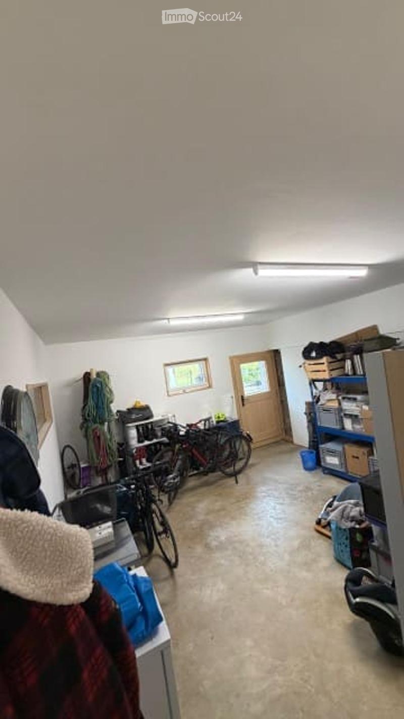 A well-lit storage or utility room with bicycles, shelves, storage boxes, and framed pictures on the walls.