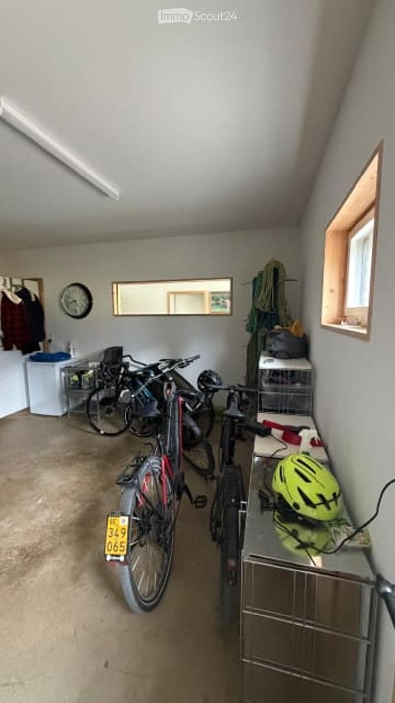 Garage with multiple bicycles, helmets, a mirror, a clock, and storage bins.