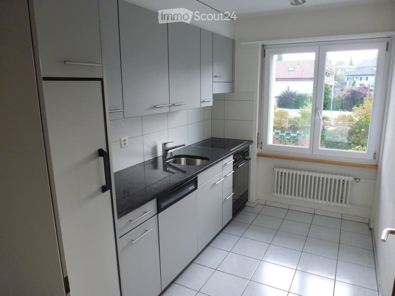 modern kitchen with white cabinets, black countertops, stainless steel sink, dishwasher, and a window with a view