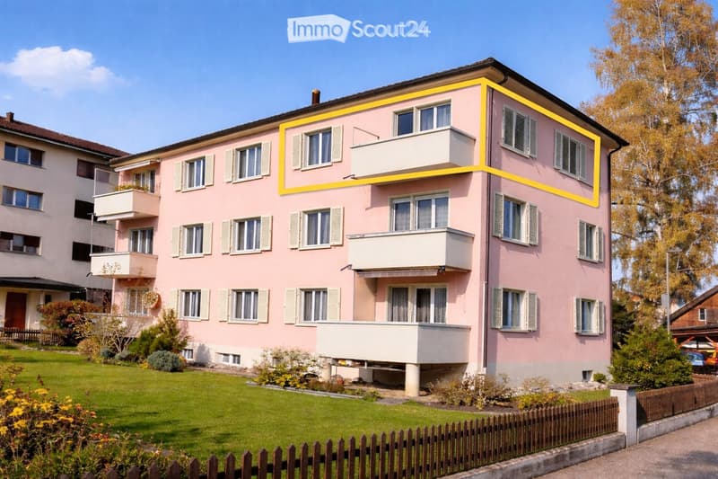 A three-story pink residential building with multiple windows, balconies, and a well-maintained garden in front.