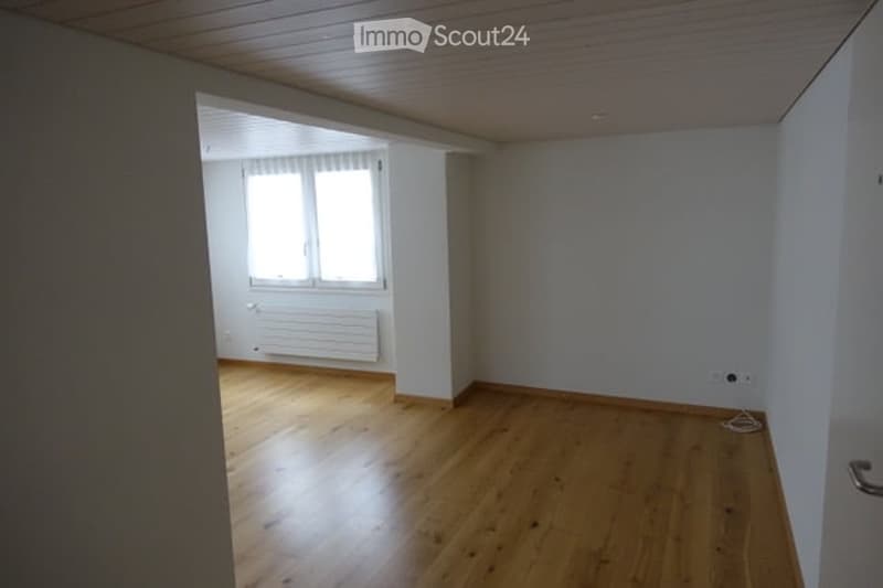 Empty room with wooden flooring, white walls, and a window with blinds. No furniture or equipment present.