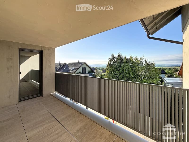 Balcony with wooden flooring, metal railing, and a view of the surrounding landscape and houses.