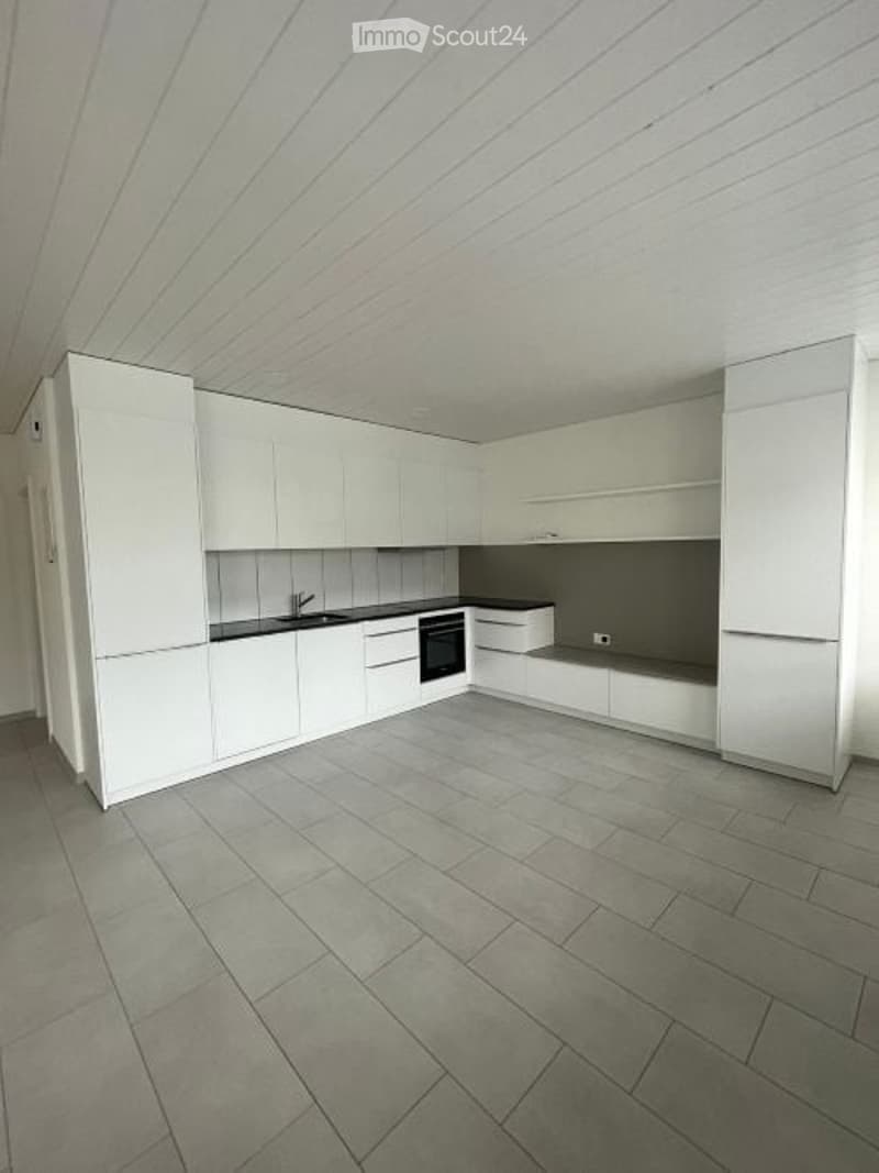 Modern kitchen with white cabinets, grey tiled floor, and built-in appliances including a sink, oven, and faucet.
