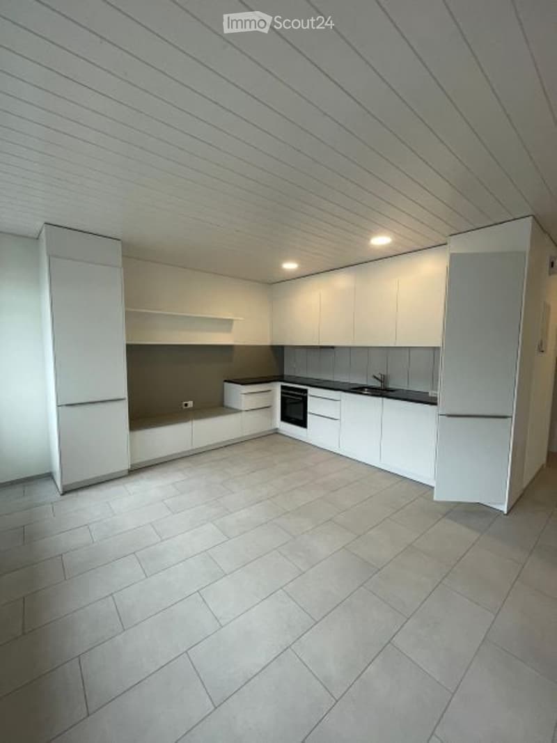 Modern, minimalist kitchen with white cabinets, a built-in refrigerator, oven, and sink. The space features a clean, contemporary design with a tiled floor and recessed lighting.