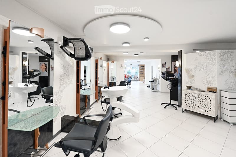 Modern salon with white tiled floors, multiple sinks, chairs, mirrors, and decorative cabinets.