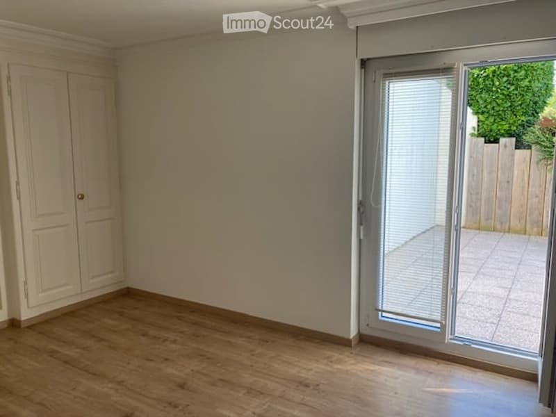 Empty room with wooden flooring, white walls, and a sliding glass door leading to an outdoor area.