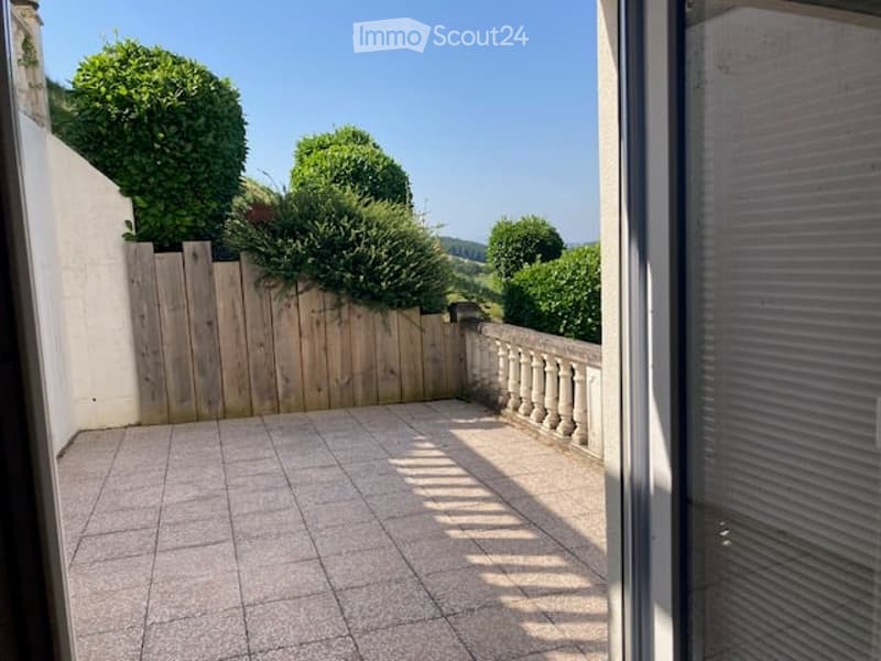 Balcony with tiled floor, wooden fence, and scenic view of greenery and hills.