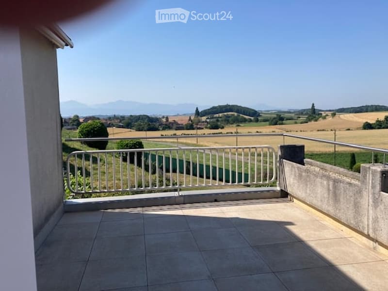 Balcony with tiled floor, metal railing, and scenic countryside view.