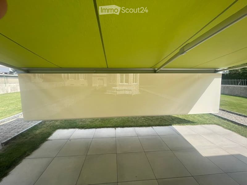 Bright green canopy with a white privacy screen, tiled floor, and grassy area visible in the background.