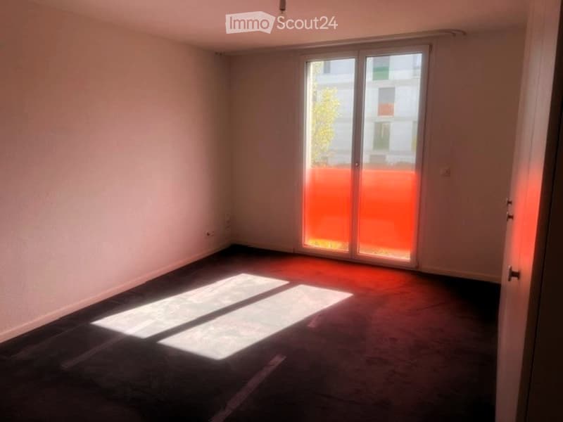 Empty room with bare walls, carpeted floor, and large sliding glass door with orange blinds.
