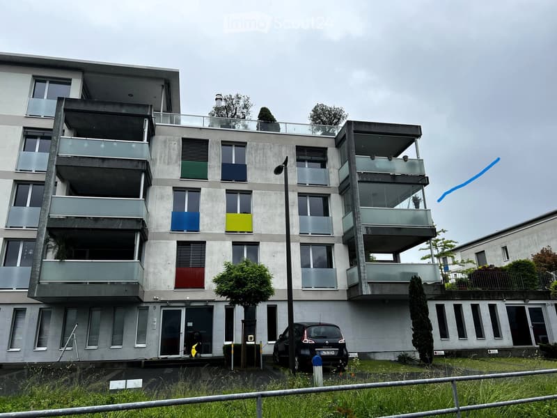 Modern multi-story apartment building with balconies, large windows, and colorful shutters.