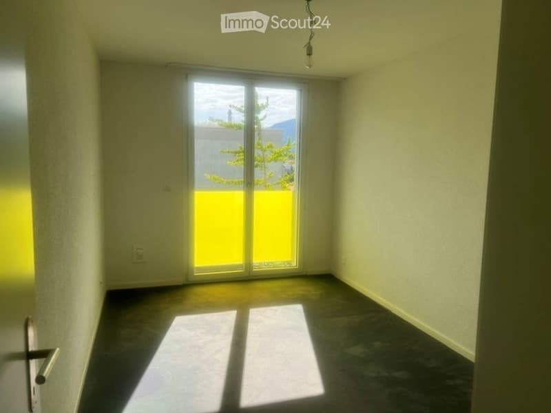 Empty room with a large sliding glass door leading to a balcony, concrete floor, and white walls.
