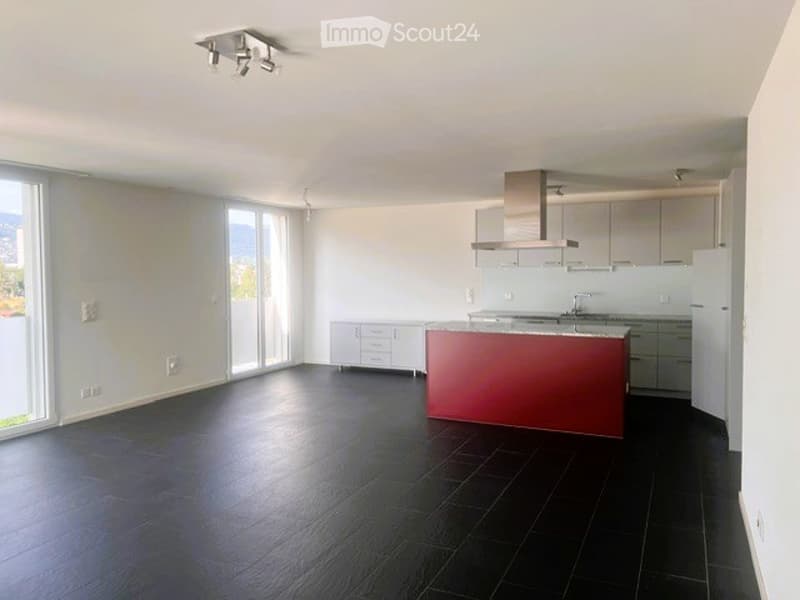 Modern kitchen with white cabinets, a red kitchen island, black tiled floor, and large windows offering a scenic view.
