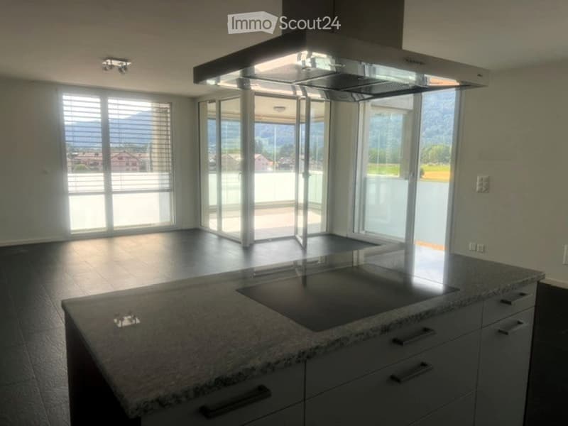 Modern kitchen with granite countertop, built-in range hood, large windows offering a scenic view, and ample cabinet space.
