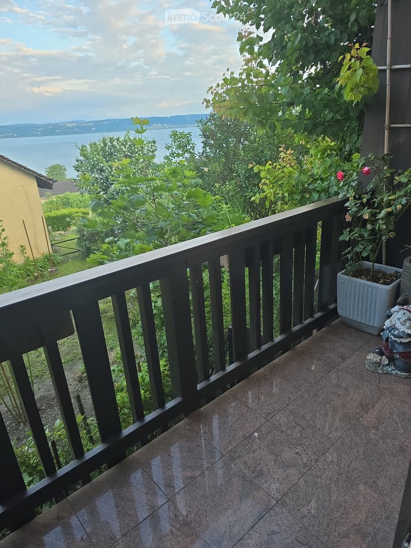 Balcony with wooden railing, tiled floor, potted plant, garden view, lake view