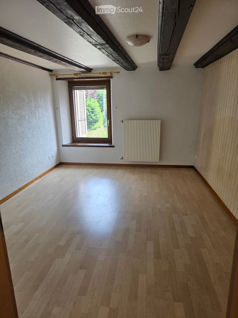 empty room, wooden floor, white walls, window, radiator, wooden beams on ceiling