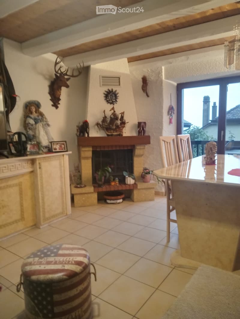 living room with fireplace, dining table, chairs, ottoman, kitchen counter, window
