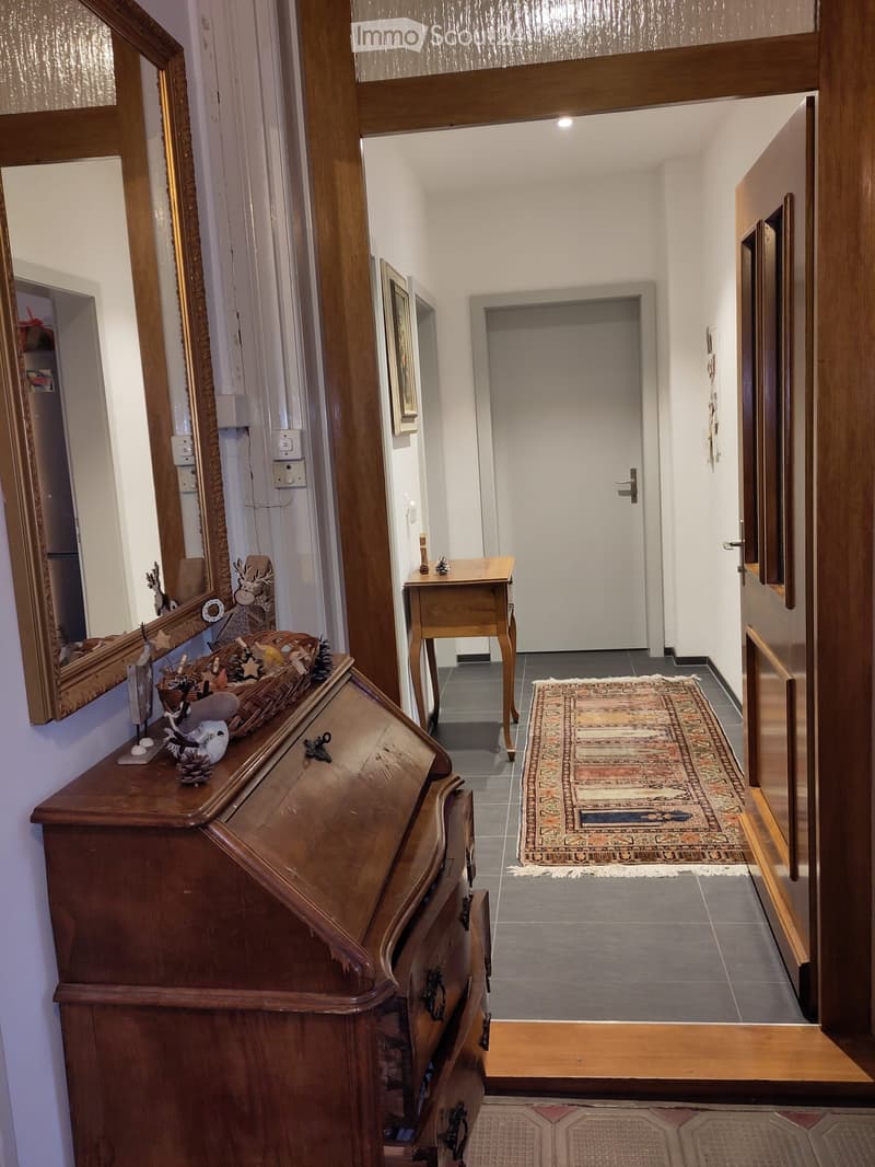 Hallway with wooden furniture, a small table, a mirror, and a decorative basket on a dresser.