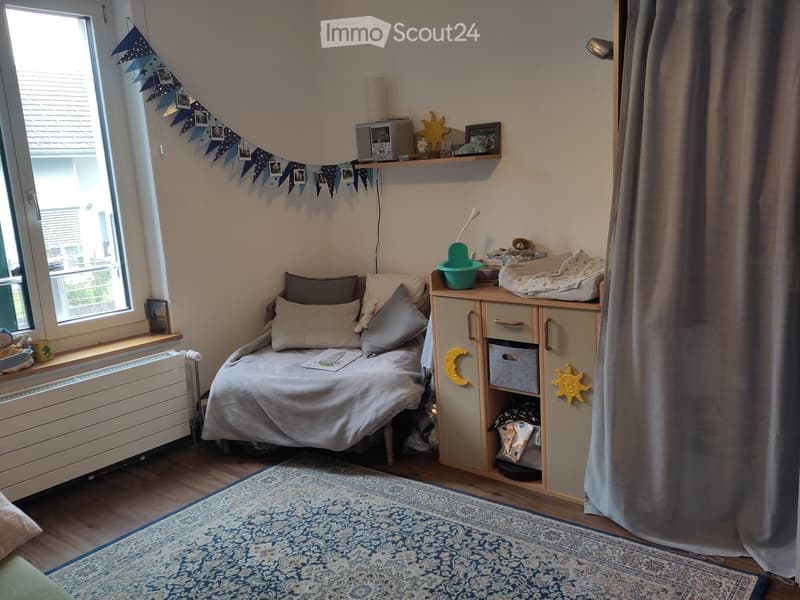 Cozy bedroom with a single bed, pillows, blanket, storage unit, and decorative items including a sun and moon design on the cabinet.