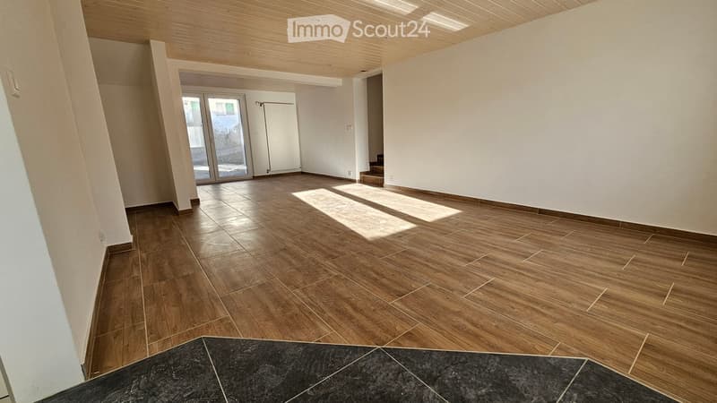 Empty room with wooden flooring, white walls, and a large sliding glass door leading to an outdoor area.