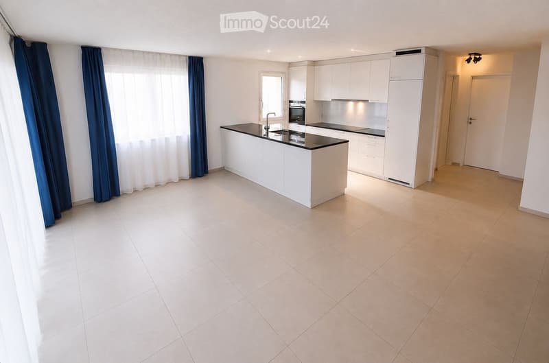 Modern kitchen with white cabinets, a central island, and a black countertop. The space features tiled flooring and large windows with blue curtains.