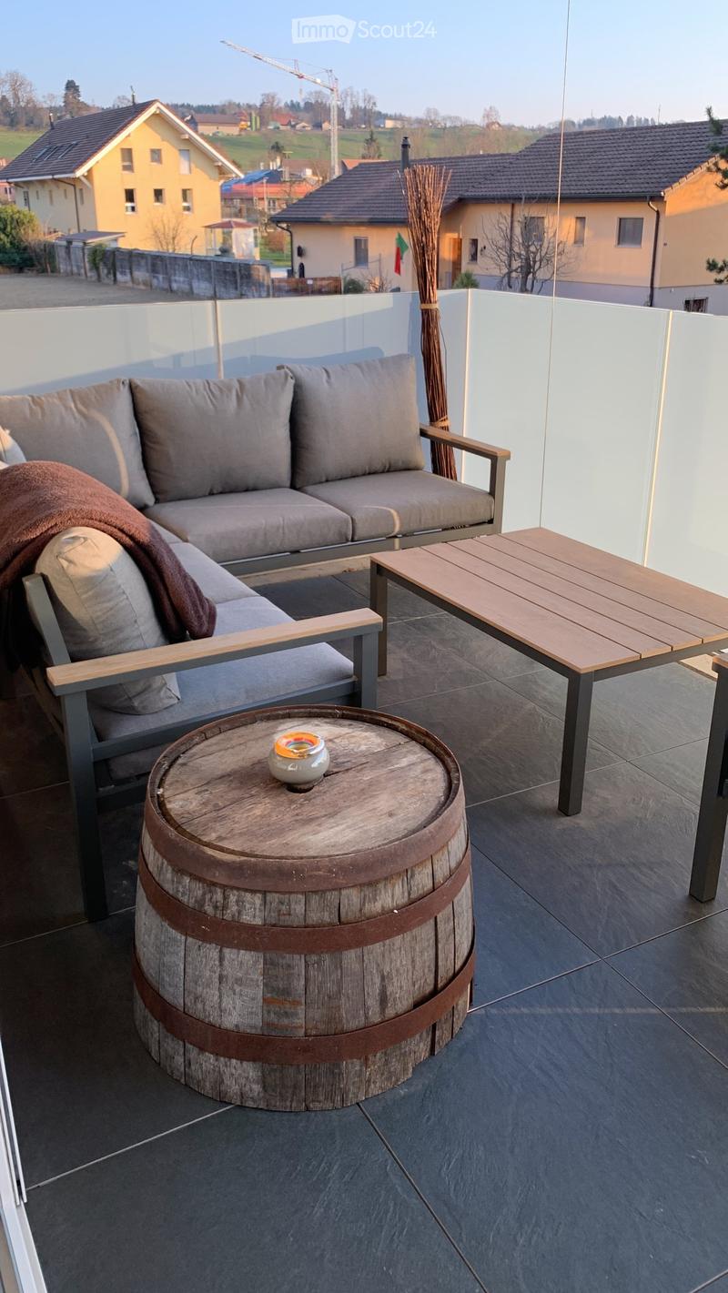 A balcony with furniture and a barrel, with a view of the village