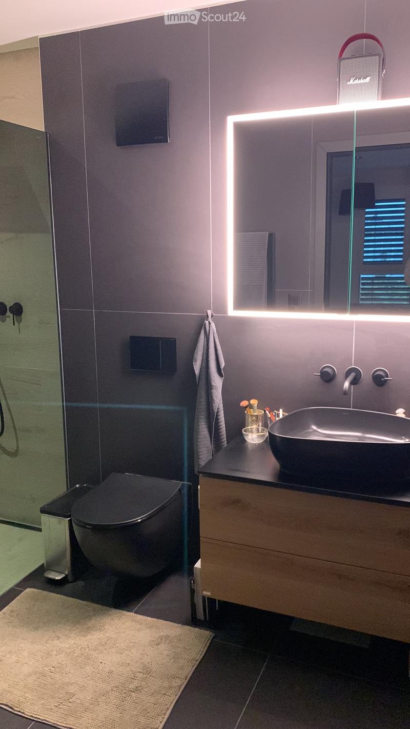 modern bathroom with tiled walls, black sink, modern mirror, and black toilet