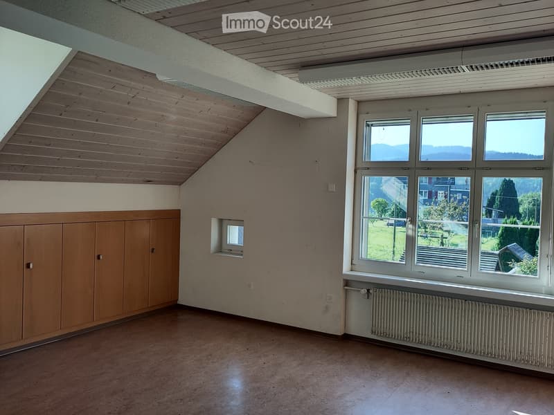 Empty room with wooden ceiling, large windows, wooden cabinet, radiator, and small window near the wall.