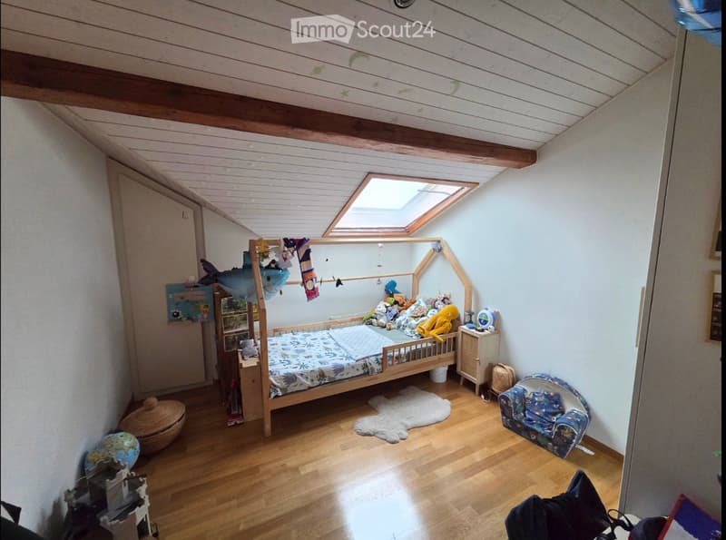 Cozy children's bedroom with wooden bed, colorful toys, a small sofa, nightstand, and a skylight window providing natural light.