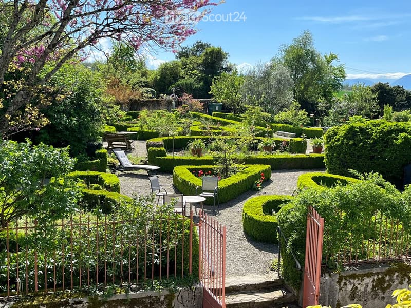 Garden / Outdoor Area. Well-maintained garden with neatly trimmed hedges, gravel pathways, and seating areas including tables and chairs.