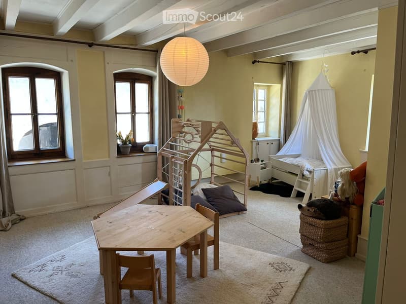 Furnished Room. Brightly lit children's room with a wooden play structure, small table and chairs, a wicker basket, and a hanging paper lantern.