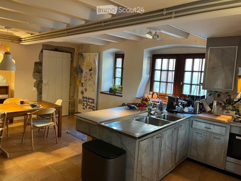 Kitchen. Bright kitchen with exposed wooden beams, large windows, marble countertops, and stainless steel appliances. Includes a dining area with a wooden table and chairs.