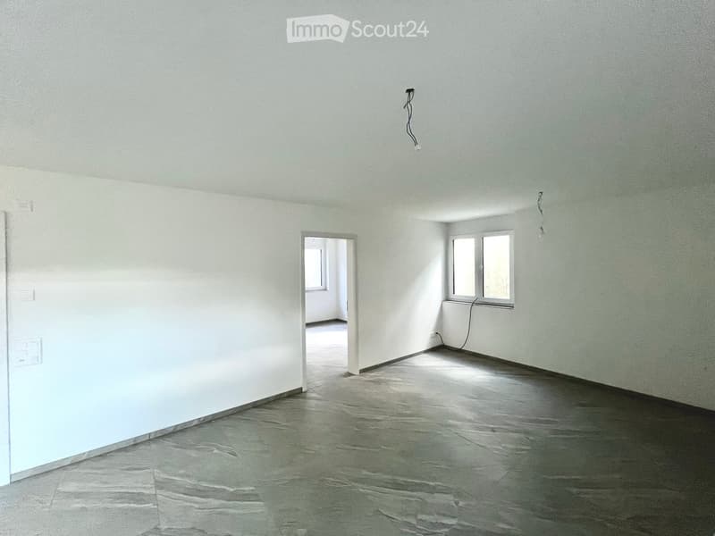 Empty room with white walls, gray flooring, two windows, and an open door leading to another room.