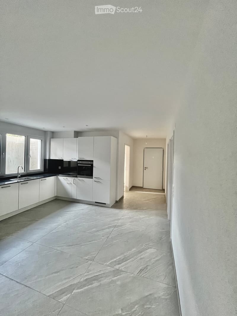modern kitchen with all white cupboards, black countertop, double oven, sink with faucet, large hallway