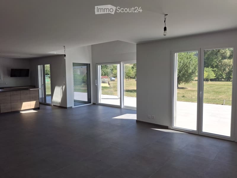 Empty room with large sliding glass doors leading to an outdoor area, tiled floor, and modern lighting fixtures.