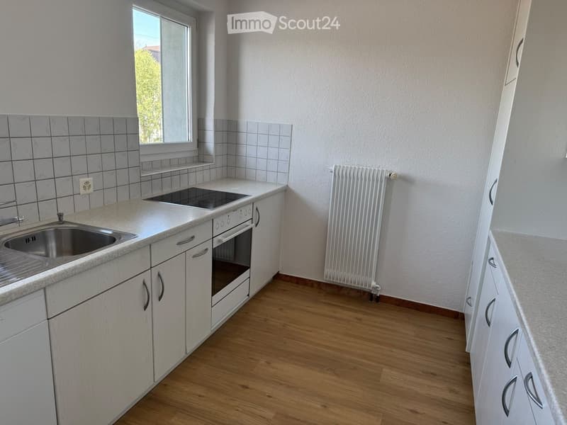 Modern kitchen with white cabinets, granite countertops, stainless steel sink, built-in oven, and radiator.