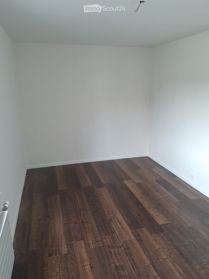Empty room with light-colored walls and dark wooden flooring. No furniture or equipment visible.