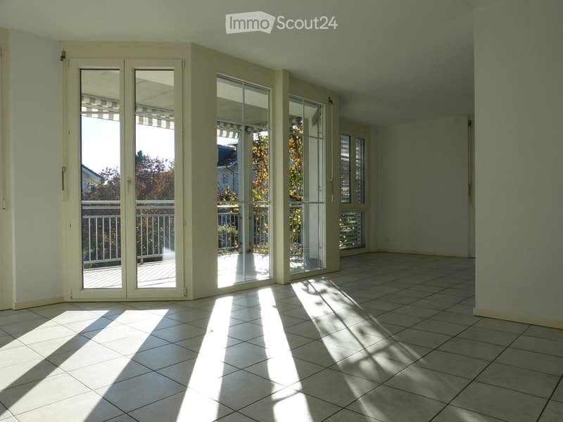 Empty room with tiled floor, large glass doors leading to a balcony, and natural light streaming in.