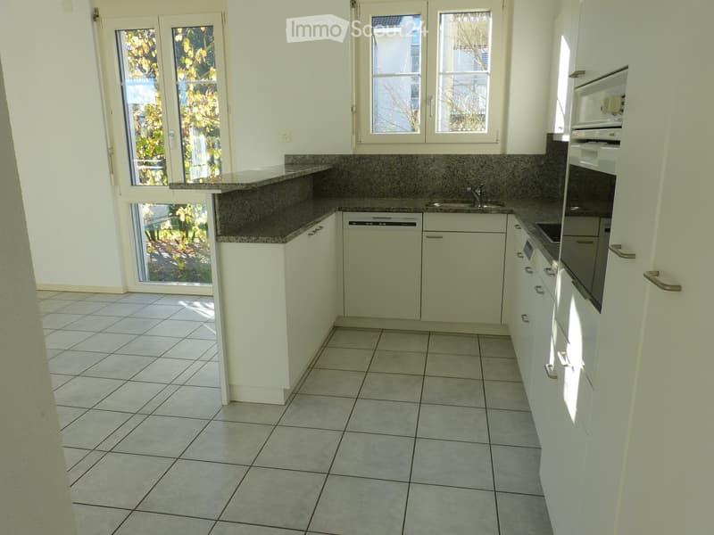 Modern kitchen with white cabinets, granite countertops, tiled floor, and large windows with blinds.