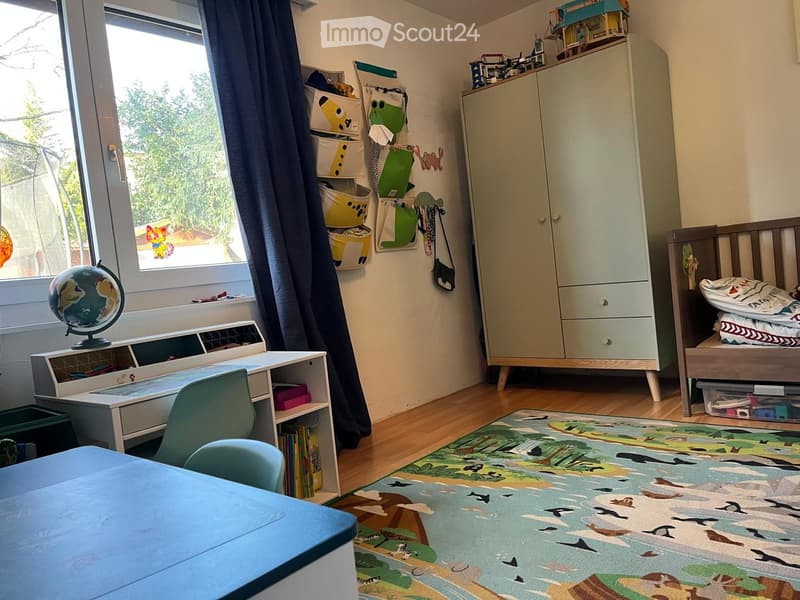 Bright, child-friendly bedroom with a wooden bed, wardrobe, desk, and colorful rug featuring animal prints.